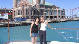 Two teenage girls posing for a photo on a charter yacht. An old building is in the background