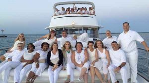 A group of men an women dressed in white outfits on the top deck of a charter yacht in Chicago IL