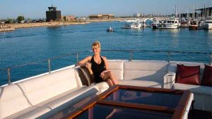 A woman sits alone posing on the top deck of the Sophisticated Lady yacht charter